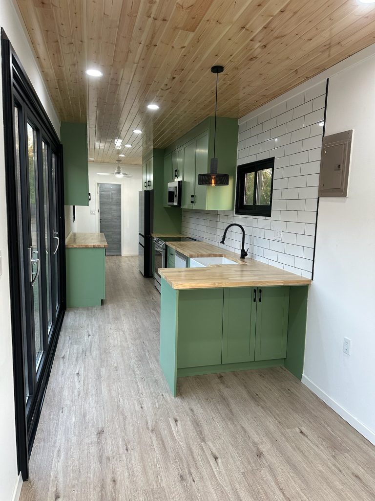 Green kitchen with a butcher block counter and glass bifold doors